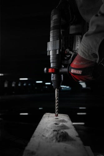 Person using a drill on a concrete block with a dark background