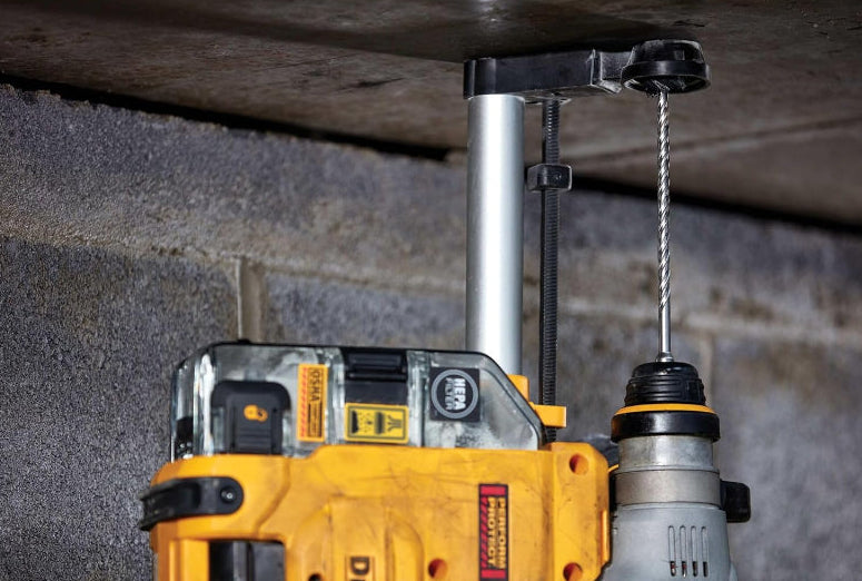Yellow power drill with a cable running through a ceiling in a concrete wall setting