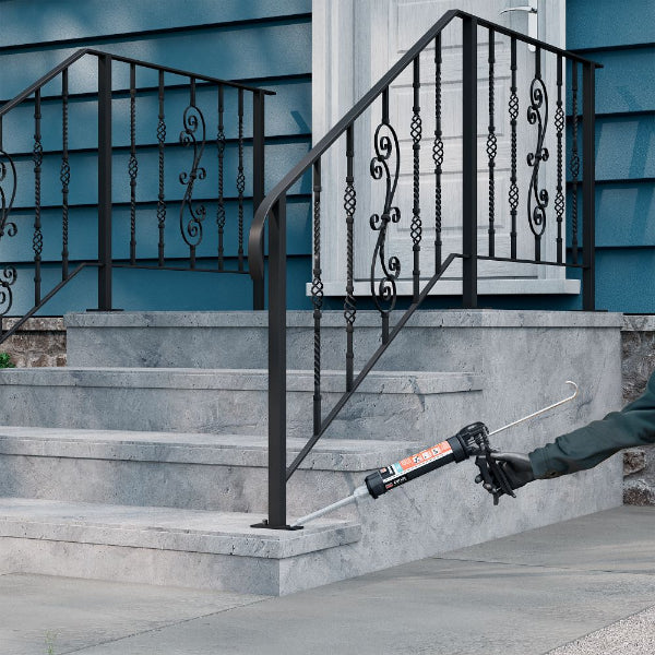 Person applying sealant to metal handrail on a staircase with blue siding.