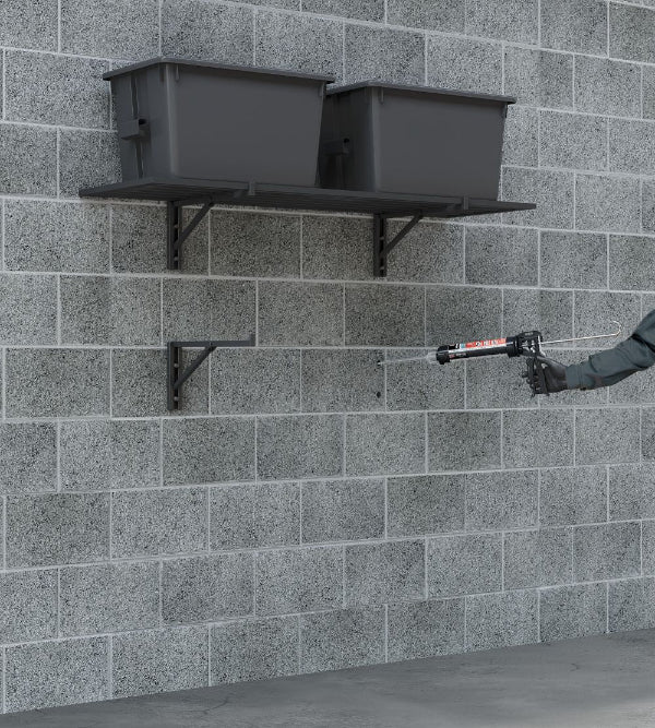 Person applying sealant to a brick wall with a caulking gun.