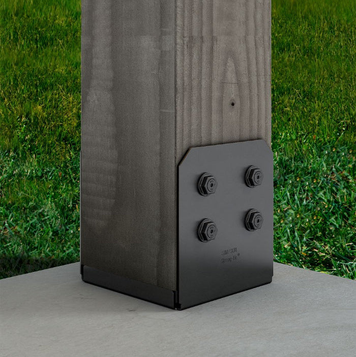Black outdoor post base on a wooden post with grass in the background