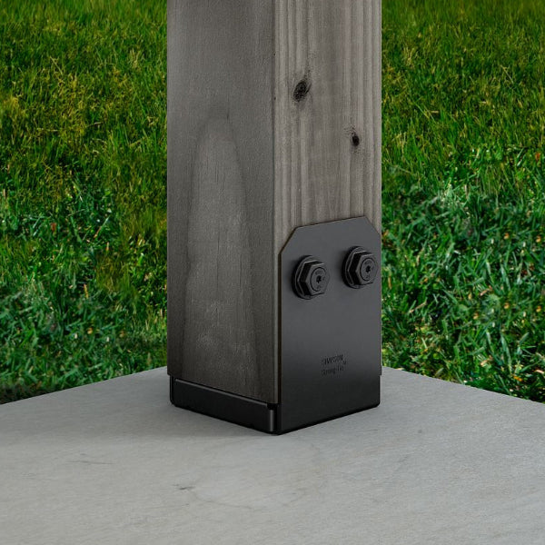 Black metal post cap on a wooden post with grass in the background