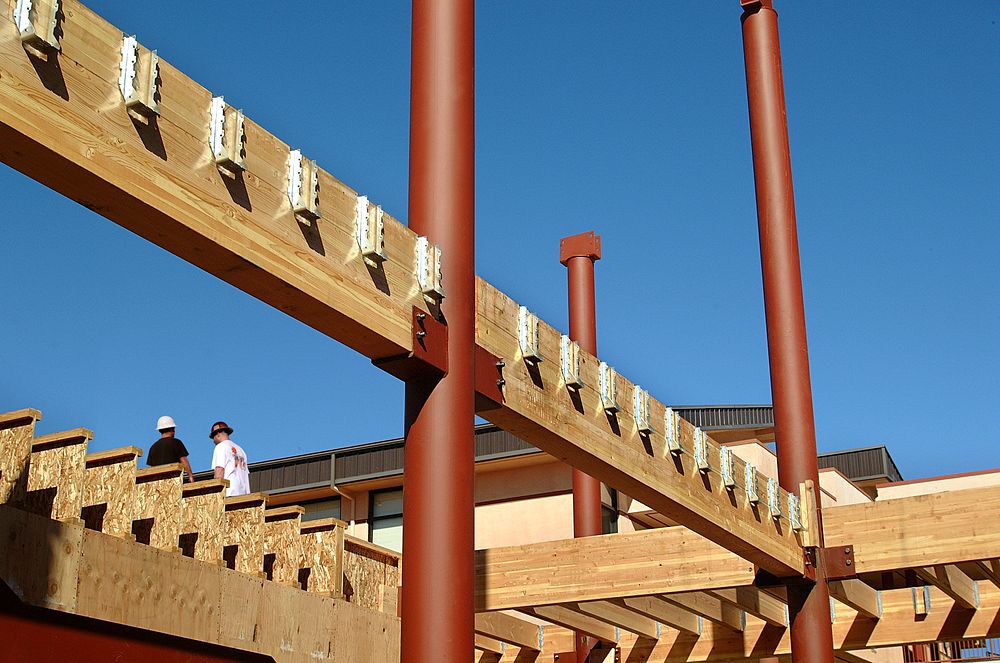 Wooden architectural structure with red beams against a clear blue sky
