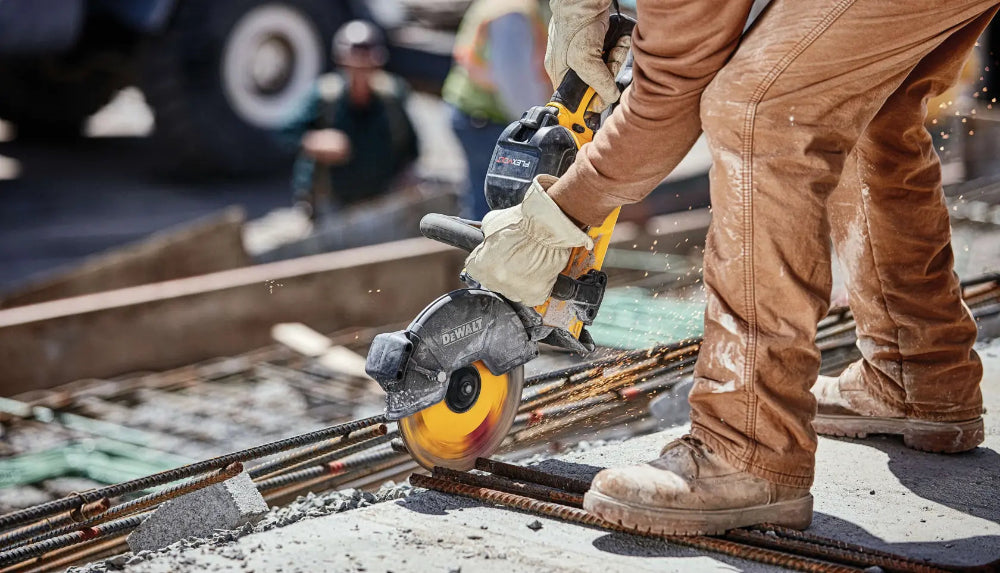 Person using a circular saw on a construction site with another person in the background.