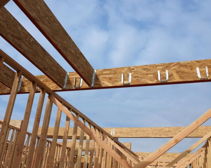 Wooden framework of a building under construction against a blue sky.
