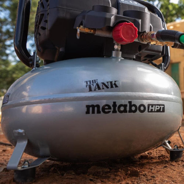 Metabo HPT air compressor on a dirt surface with trees in the background