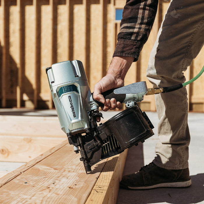 Person using a Metabo HPT nail gun on wooden planks