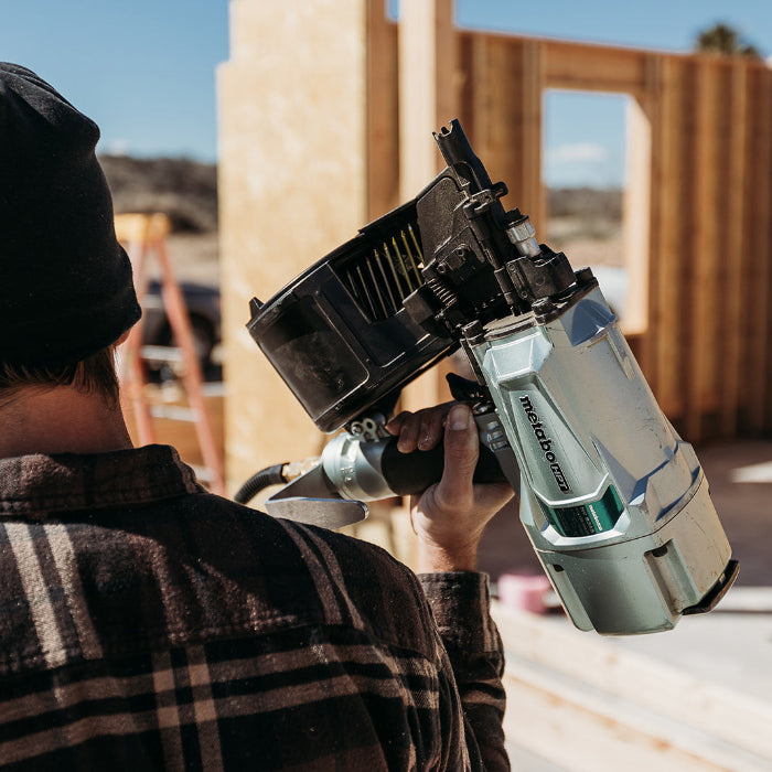 Person holding a power tool in front of a construction site