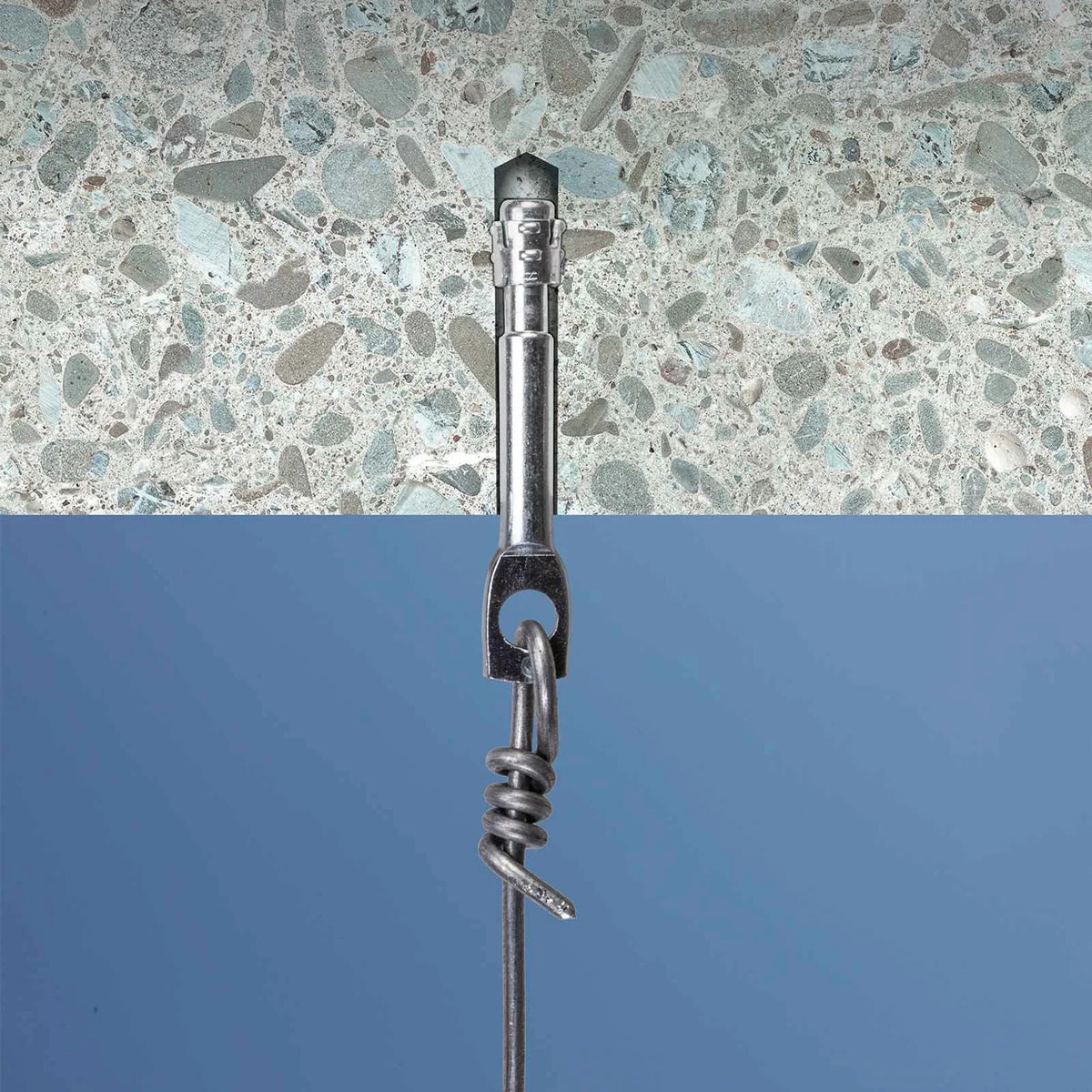 A close-up of a metal wall anchor or toggle bolt installed against a speckled stone-patterned surface, with a blue background visible below.